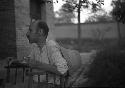 Man seated in chair eating and holding teacup