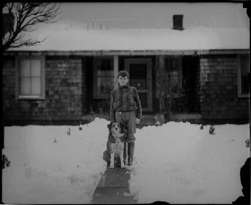 Boy and dog in front of house