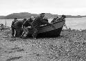 Men pushing dory onto land