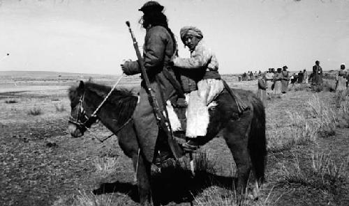 Mounted soldier with child behind on saddle