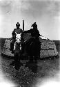 Two men on horses wearing conical hats