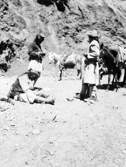 Three caravaneers standing or sitting