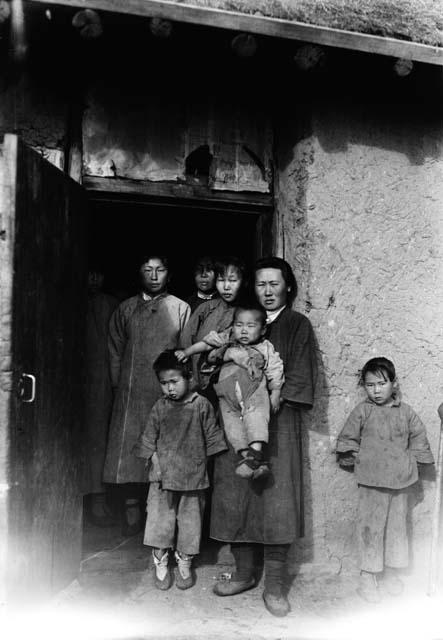 Women and children standing doorway of a building