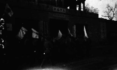 Soliders with flags marching in front of city gate