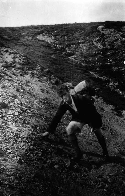 Man with pack on back climbing hill