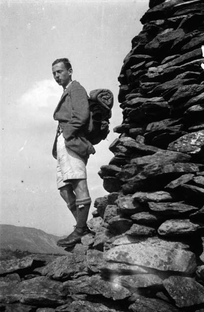 Man with pack on back standing on rocks