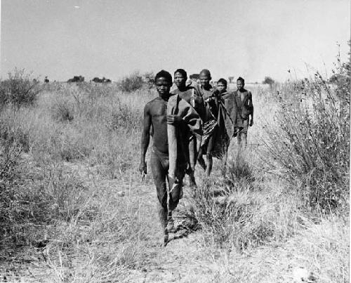 Men of a visiting band from Okwa walking in a line