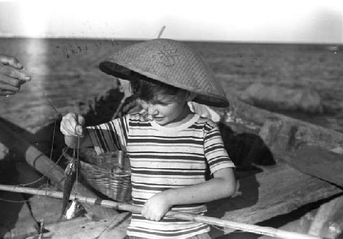 David Lattimore, on boat, holding a little fish and a fishing pole