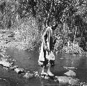 Masai native crossing stream on stepping stones