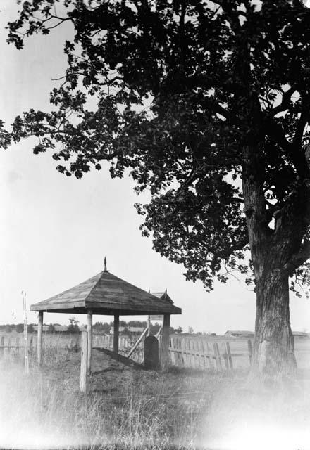 Small open structure over mound and stone marker