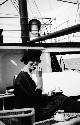 Woman holding cup and sitting on deck of ship