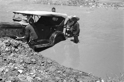 Men pushing car out of the river