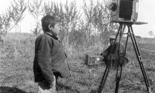 Portrait of a boy with hump back looking at camera on a tripod