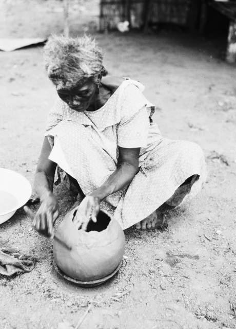 Pottery making, smoothing pottery after adding clay roll