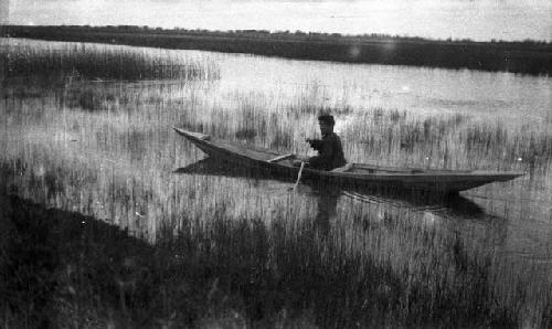 Fish skin boy in a canoe along the edge of the river