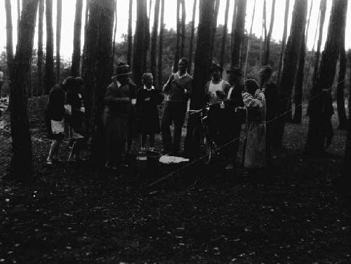 Men and women in woods excavating site