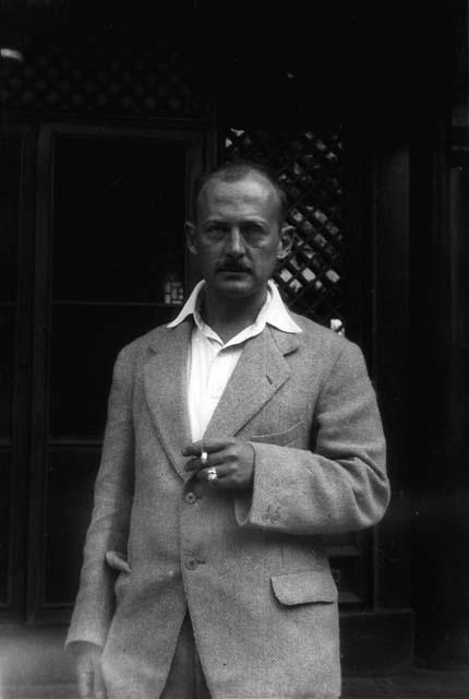 Owen Lattimore in suit jacket, holding cigarette