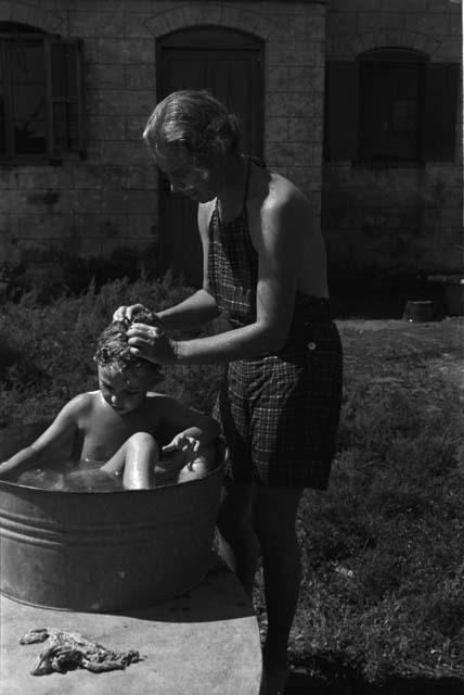 David Lattimore sitting in basin with Eleanor washing his hair