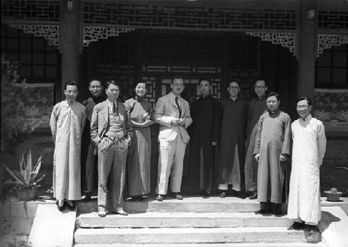Nine men and one woman standing on steps of porch