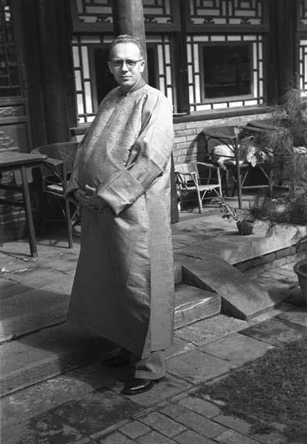 Man posing in long robe and big belly on step of building