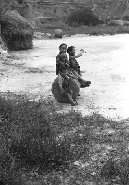 Four children on and by a cylinder