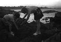 Eleanor and David Lattimore climbing on rocks by sea or lakeshore