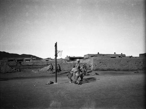 Gegenmiao, men playing basketball, mud brick buildings in background