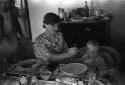 Western woman sitting indoors at table feeding baby