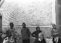 Group of seven people standing by brick building wall