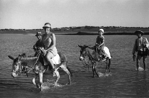 Two men walking, Eleanor Lattimore and David Lattimore riding donkeys