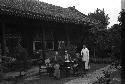 Eleanor Lattimore, a man and a woman seated at table in courtyard