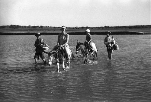 Two men walking, Eleanor Lattimore and David Lattimore riding donkeys