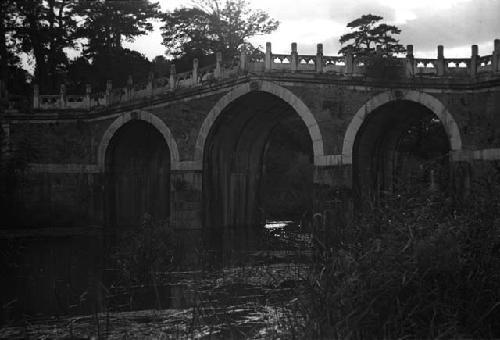 Lateral view of large stone bridge with three arches over river