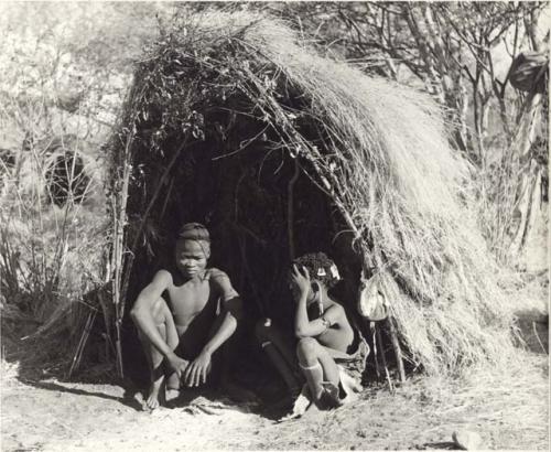 Tsamgao and Bau sitting in front of their skerm (print is a cropped image)