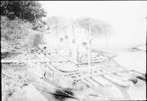 River with men working on boats and canoes