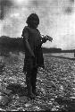 Man standing on river rocks with plant in hands