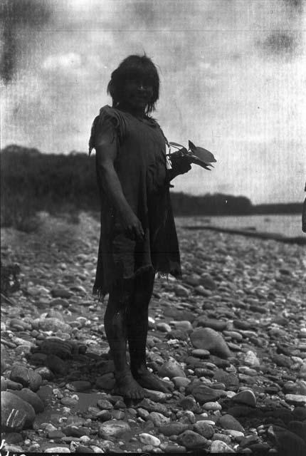 Man standing on river rocks with plant in hands