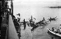 Canoes and boats moving towards large ship