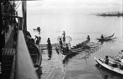 Canoes and boats moving towards large ship