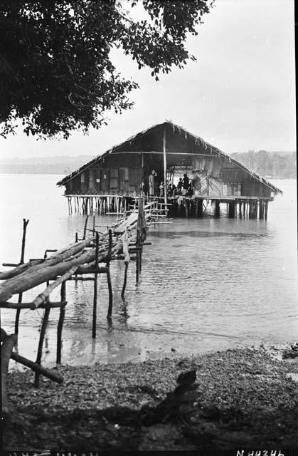 House on stilts over water with log walkway