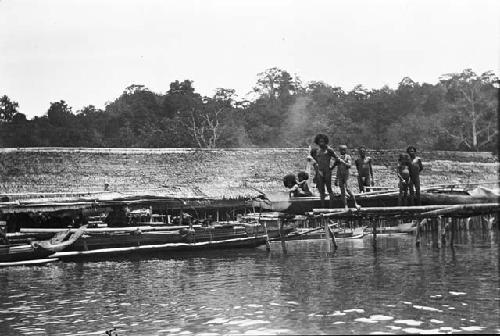 Men standing on dock with boats and canoes