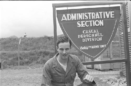 Man sitting in front of sign outdoors clinching his fist