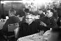 Priest and men sitting at tables looking ahead