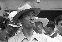 Man in top hat looking ahead within a bunched crowd