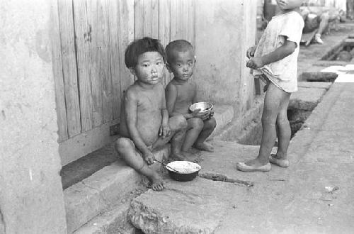 Nude children eating food together