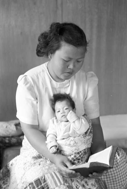 Woman holding baby in lap while reading