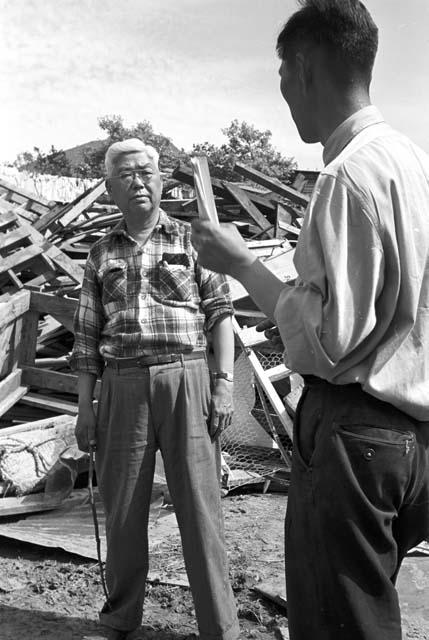 Two en speaking with each other, rubble in background