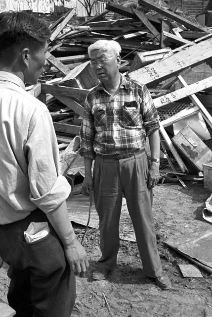 Two en speaking with each other, rubble in background