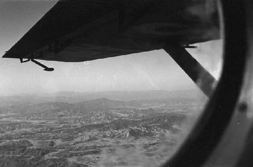 Plane wing and mountains through window