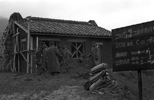 Workers piling dirt outside of house